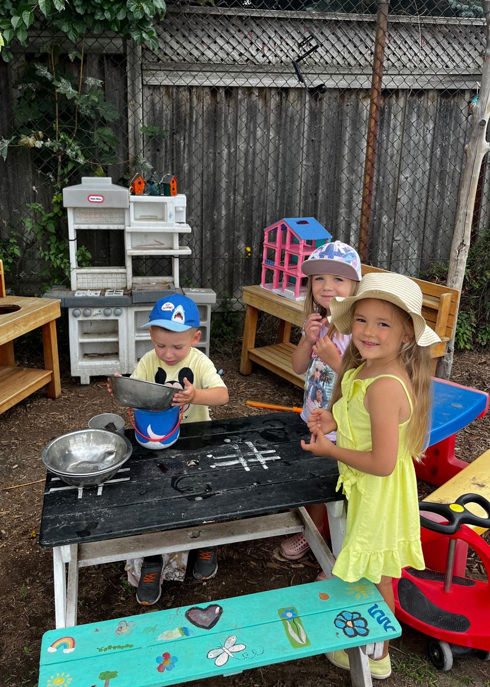 Little campers cooking in the outdoor play kitchen